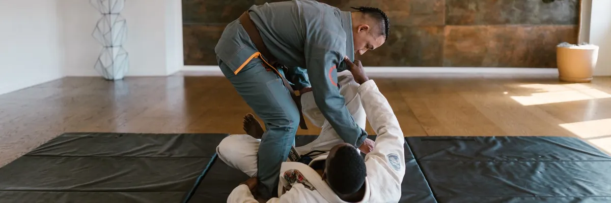 Jiu-jitsu partners drilling a guard pass on black mats