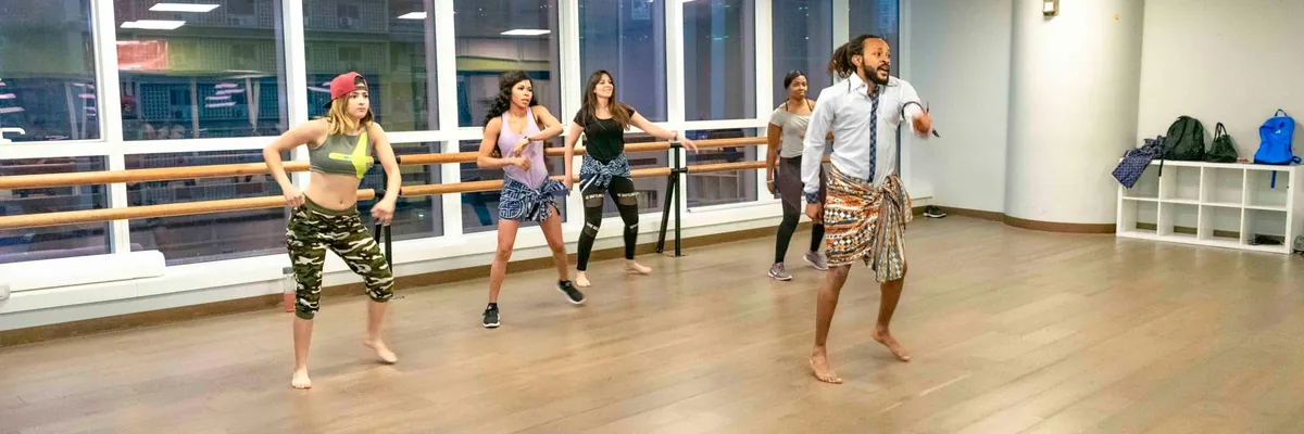 Instructor leading a dance class in a bright mirrored studio