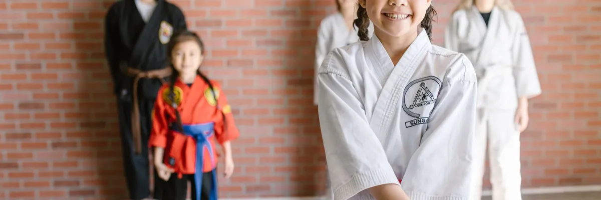 Children in karate uniforms lined up in a dojo with their instructor