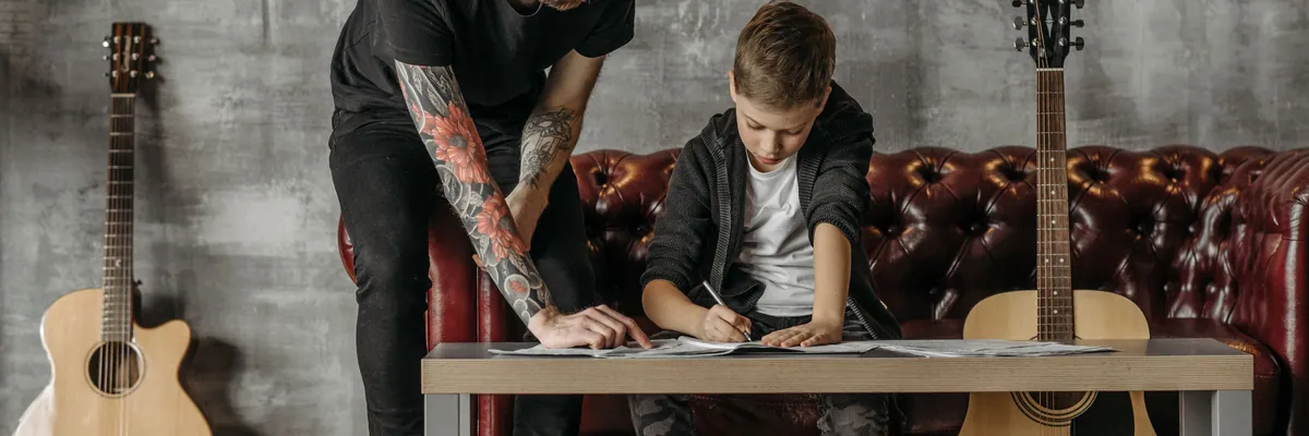 Guitar teacher helping a boy with written notes, acoustic guitars on either side