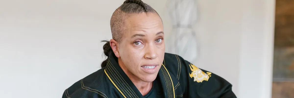 Martial artist in a black embroidered uniform in a dojo