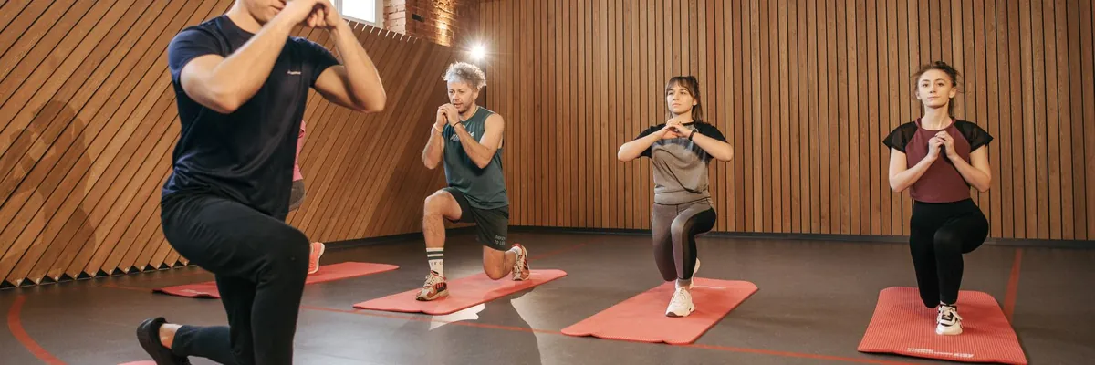 Adults exercising on red mats in a wood-paneled studio
