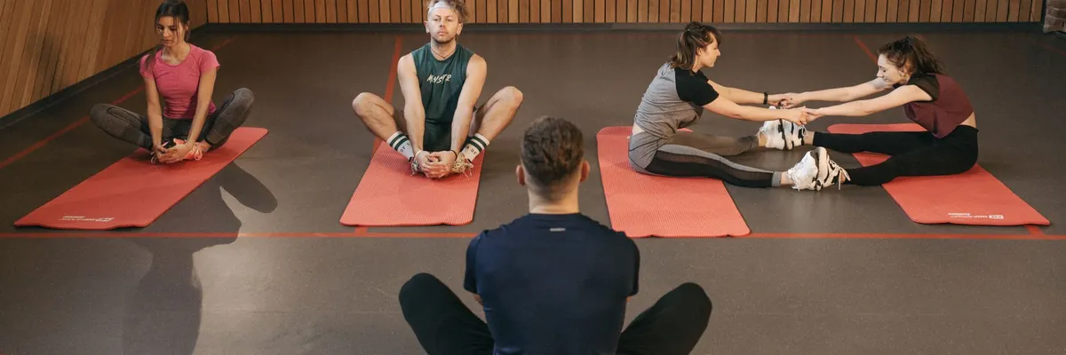 Yoga class stretching on red mats in a wood-paneled studio